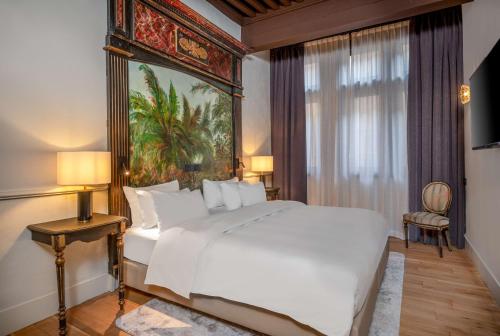 a bedroom with a white bed and a painting on the wall at Cour des Loges Lyon, A Radisson Collection Hotel in Lyon