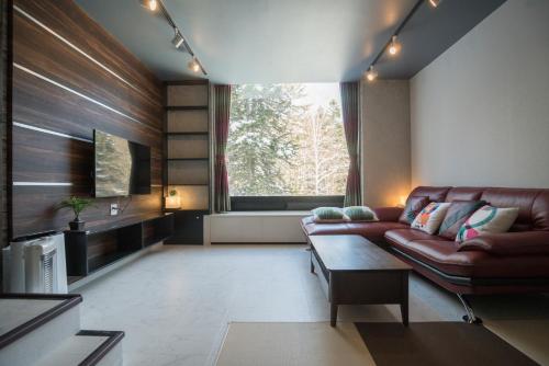 a living room with a leather couch and a window at 星野度假村Village Alpha Tomamu复式公寓套房 in Tomamu