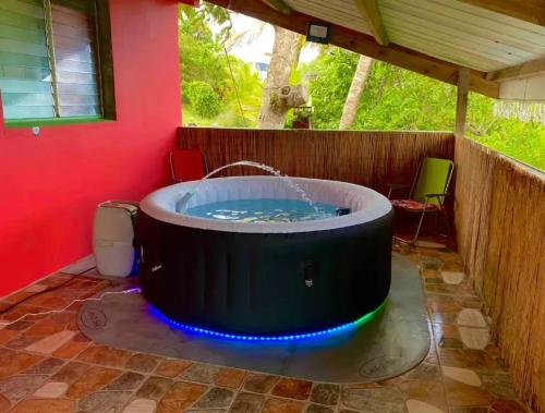 a hot tub in a room with a red wall at Maison de charme au Robert avec spa et vue sur mer in Le Robert