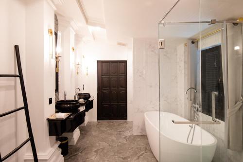 a white bathroom with a tub and a sink at Perana Wellness Resort Chiang Mai in Ban Thung Pong