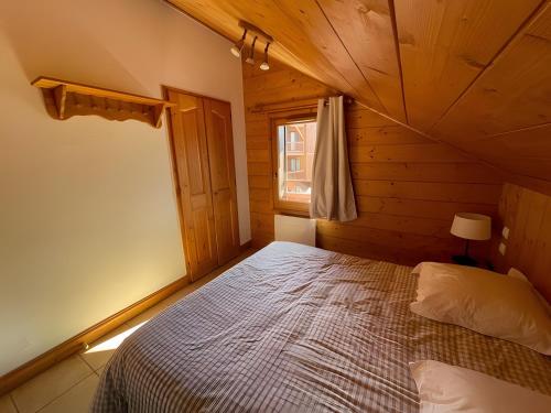une chambre avec un lit dans une cabane en bois dans l'établissement Appartement Les Airelles, à Levassaix