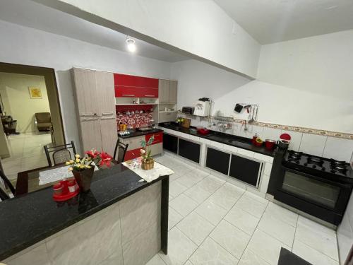 a large kitchen with red cabinets and a black counter top at Residencial Esperança in Nova Iguaçu
