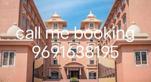 un grand bâtiment rose avec l'inscription « Appelez-moi pour réserver » dans l'établissement Marquis Beach Resort, à Candolim