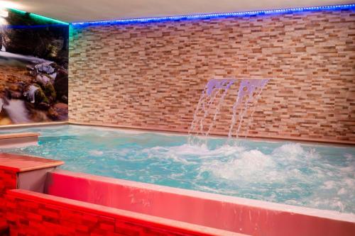 a hot tub with a fountain in a brick wall at Olympic regina hotel in Pinzolo