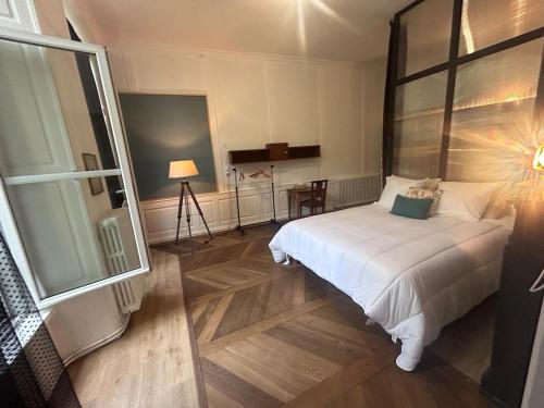 Un dormitorio con una cama blanca y una ventana grande. en la maison des dames, 