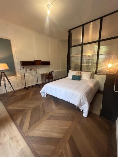 a bedroom with a large white bed with a large window at la maison des dames in Poussay