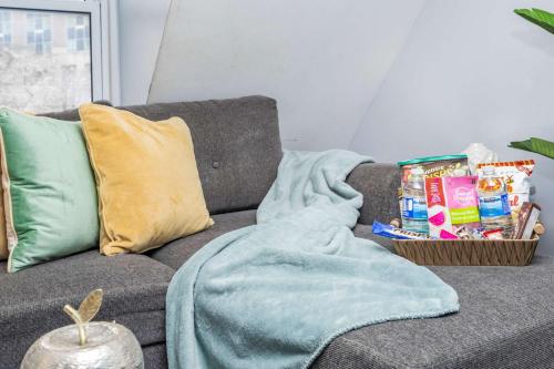 a blanket on a couch with a basket of snacks at Urban 1BR Gem with Kitchen, Smart TV & Workspace in Ottawa