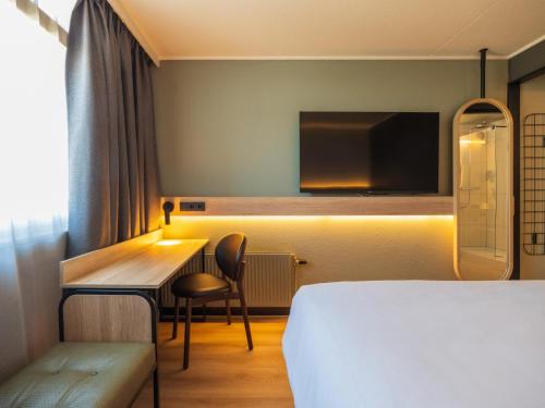 a hotel room with a bed and a desk and a tv at Campanile Hotel & Restaurant Breda in Breda