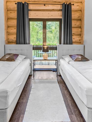 two beds in a room with a table and windows at Ferienblockhaus Schwarzwald - Luxus Chalet mit Sauna & Whirlpool in Feldberg
