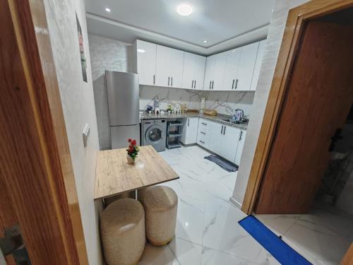 Una cocina con gabinetes blancos y una mesa en ella. en Appartement idéal à El Jadida pour les familles, en Sidi Bouzid