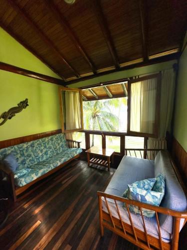 a living room with a couch and a window at Tree House Inn Ocean Front Unit #2 in Sámara