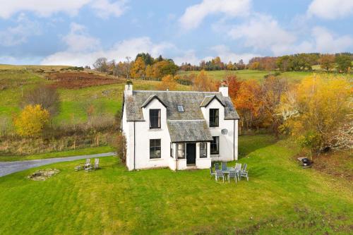 ein kleines weißes Haus auf einer Wiese in der Unterkunft Milton of Tullypowrie Cottage in Pitlochry