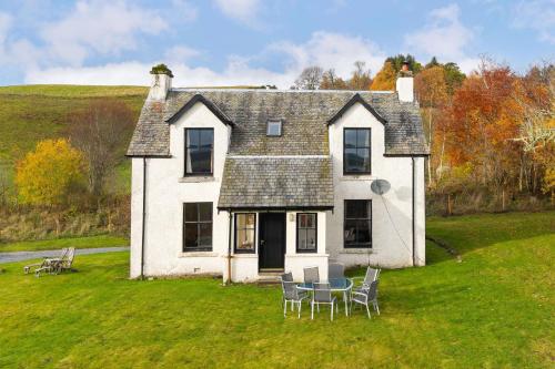 a house with a table and chairs in front of it at Milton of Tullypowrie Cottage in Pitlochry