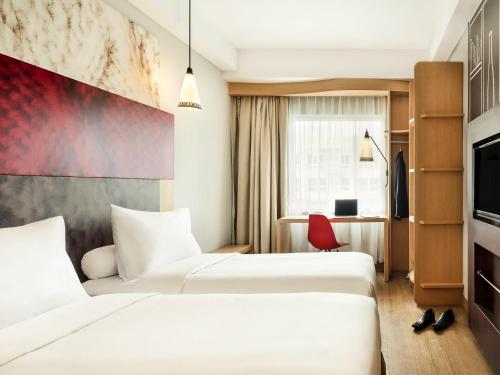 日惹ibis Yogyakarta Adi Sucipto的一间有两张床和一台电视的酒店房间