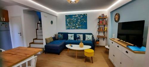 ein Wohnzimmer mit einem blauen Sofa und einem Tisch in der Unterkunft Colorful House Tsoutsouras in Tsoútsouros