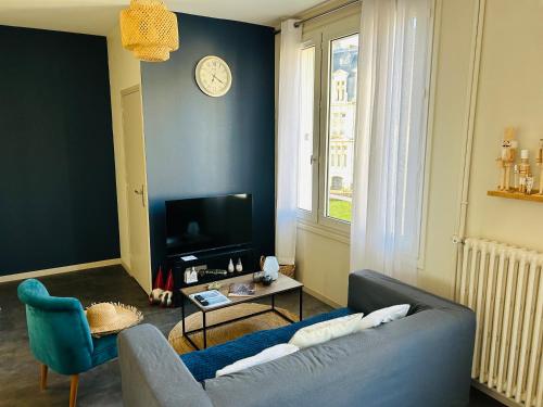 a living room with a couch and a clock on the wall at Le 5 - Spacieux 2 pièces Caen Centre Le Port in Caen