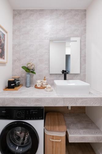 a bathroom with a sink and a washing machine at Arena - El Silencio Apartamentos in Castañeras
