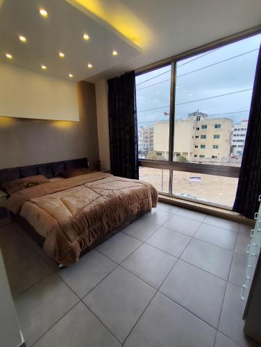 een slaapkamer met een bed en een groot raam bij Gentle Breeze Studio 3 in Amman