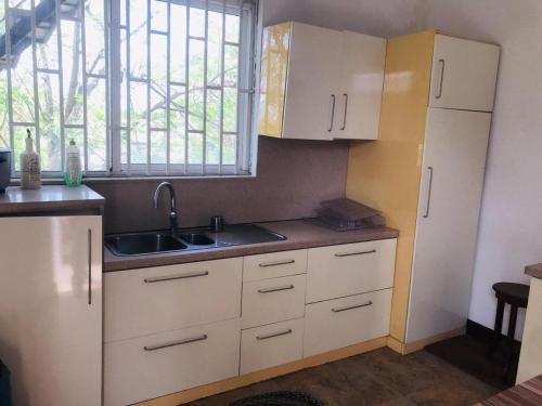 une cuisine avec des armoires blanches, un évier et une fenêtre dans l'établissement The Triantha, 