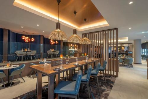 a restaurant with a long table and blue chairs at Clayton Hotel Cardiff Lane in Dublin
