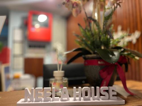 a sign that says need a house with a vase with flowers at Neela House in Labuan