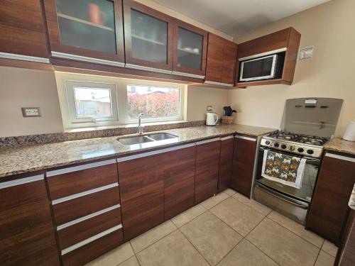 a kitchen with wooden cabinets and a sink and a stove at CasaDelSUr in San Carlos de Bariloche