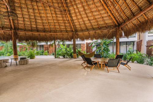 CedroにあるDivine 2BR with Beach Access Gym Fast WiFiの藁葺き屋根の下にテーブルと椅子が備わるパティオ