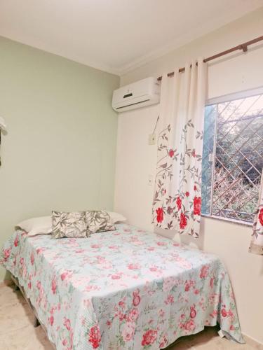 een slaapkamer met een bed met een bloemenbed en een raam bij Casa Parque Verde Cop30 in Belém