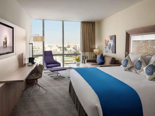 a hotel room with a large bed and a desk at Novotel Jeddah Tahlia in Jeddah
