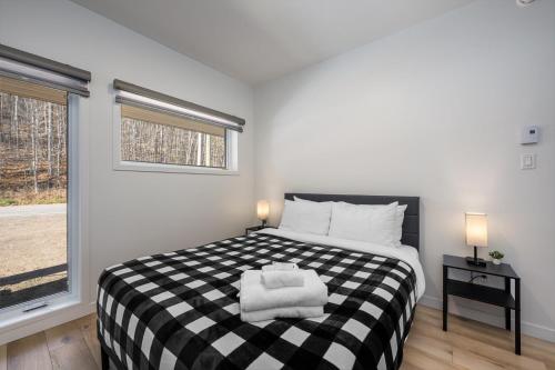 a bedroom with a black and white bed with a window at Havre du Loup: St. Lawrence River Views & Trails in Petite-Rivière-Saint-François