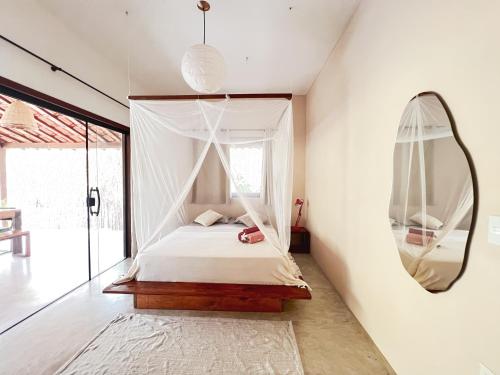 a bedroom with a canopy bed and a mirror at Casa Gemini in Ilha de Boipeba
