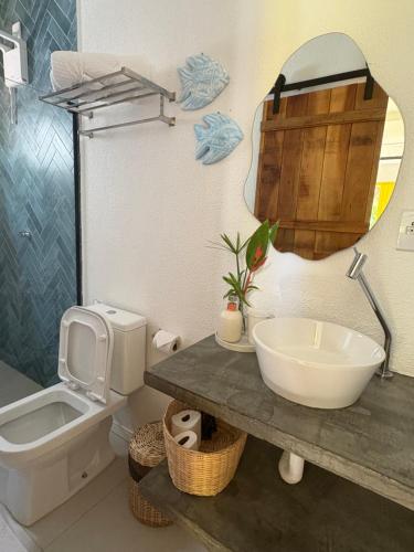 Un baño con lavabo, inodoro y espejo. en Villa Tropicana, en Saubara