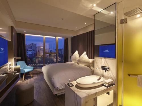 een hotelkamer met een bed en een badkamer met een raam bij Mercure Yangzhou Dongguan Street in Yangzhou