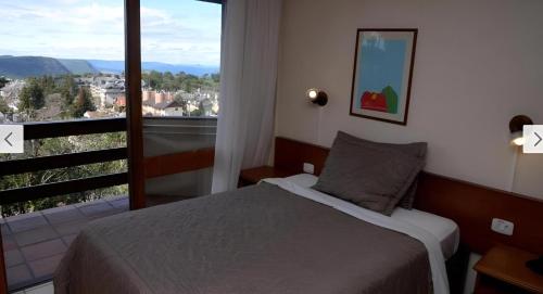 una camera da letto con un letto e una grande finestra di Apartamento Esquina Rua Torta, Pousada do Serrano, Gramado, RS a Gramado