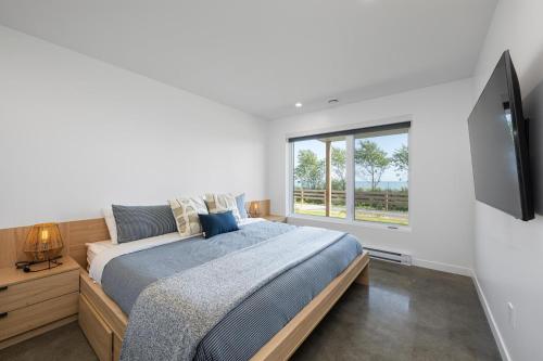 ein Schlafzimmer mit einem Bett und einem großen Fenster in der Unterkunft Mer et Mont 1223: Spa & River Views Near Le Massif in Petite-Rivière-Saint-François