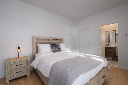a white bedroom with a large bed and a mirror at Panorama 1249: Garden-Level with Fireplace in Petite-Rivière-Saint-François