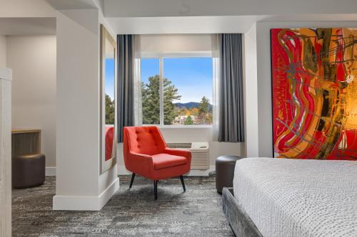 a bedroom with a red chair and a window at Lake Placid Inn Boutique Hotel in Lake Placid