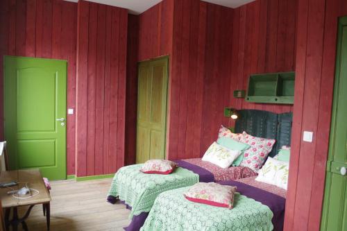 a bedroom with red walls with two beds and a tv at L'école est finie ! in Féron