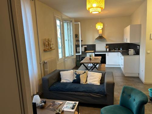 a living room with a couch and a kitchen at Le 5 - Spacieux 2 pièces Caen Centre Le Port in Caen