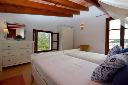 - une chambre avec 2 lits, une commode et des fenêtres dans l'établissement Encantadora finca con piscina en la naturaleza, à Caimari