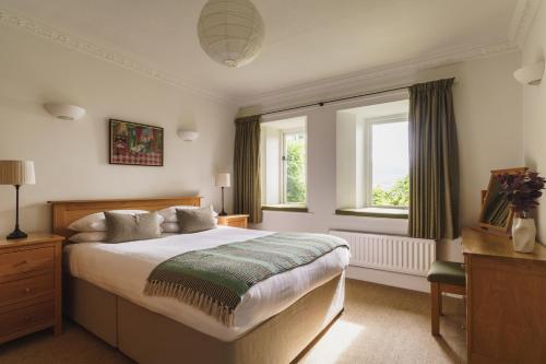 a bedroom with a large bed and two windows at 2 Hart Head Barn, Renovated Barn, Ambleside in Rydal