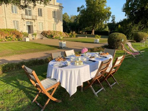 a table with a white table cloth and chairs in front of a building at Le Petit Serrant - maison d'hôtes d'exception in Bouchemaine