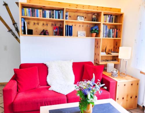 Sofá rojo en la sala de estar con estantería en Curtins18, en Pontresina