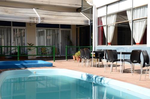 a swimming pool with chairs and a table next to a house at Hotel Italia in Villa Carlos Paz