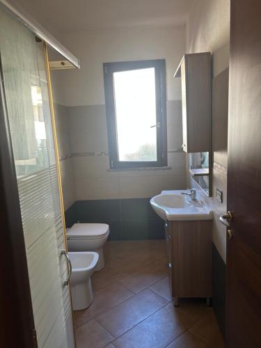 a bathroom with a toilet and a sink and a window at Le Mille e Una Notte II in Olbia