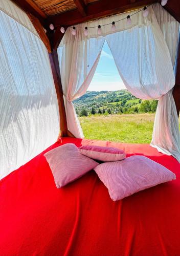 ein rot-weißes Bett in einem Zelt mit einem Fenster in der Unterkunft A-Frame Haven in Dealu Muntelui