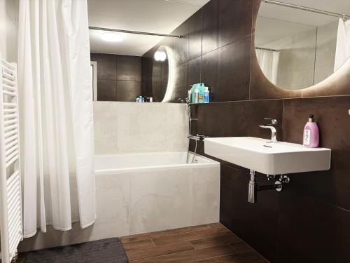 ein Badezimmer mit Waschbecken, Badewanne und Spiegel in der Unterkunft Skyluxe Loft Eurovea Tower Free Parking in Ovsište