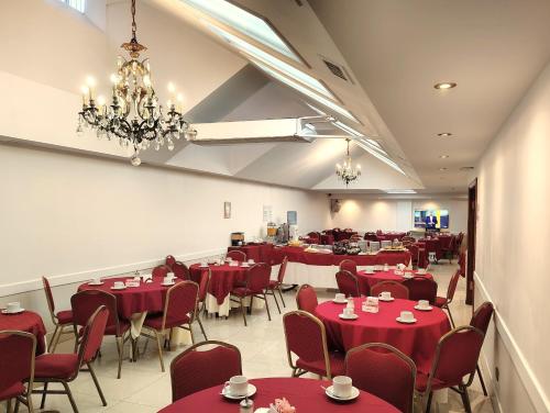 un comedor con mesas y sillas rojas y una lámpara de araña en Hotel Guerrero, en Mar del Plata