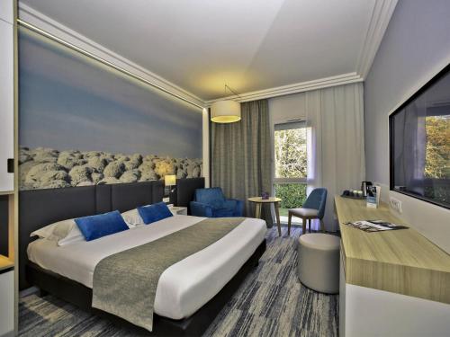 a hotel room with a bed and a television at Mercure Castres L'Occitan in Castres