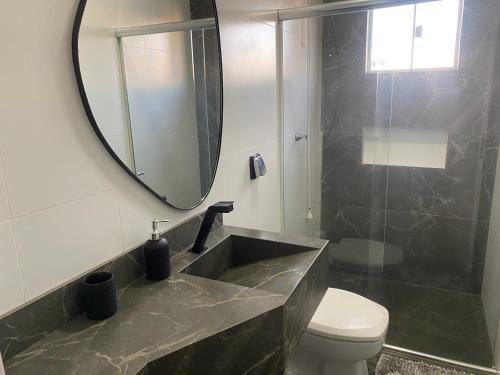 une salle de bain avec un lavabo et un miroir et des toilettes dans l'établissement Quarto Em Sobrado - Banheiro INDIVIDUAL, Garagem Coberta e TV com streamings, à Campo Mourão